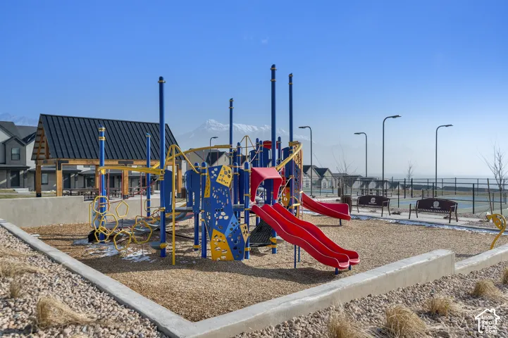 Community playground featuring multiple slides and climbing structures, a covered pavilion, and outdoor benches