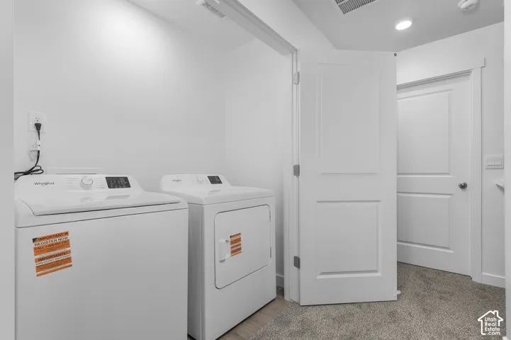 Laundry area with white walls, recessed lighting, and wood-finish flooring