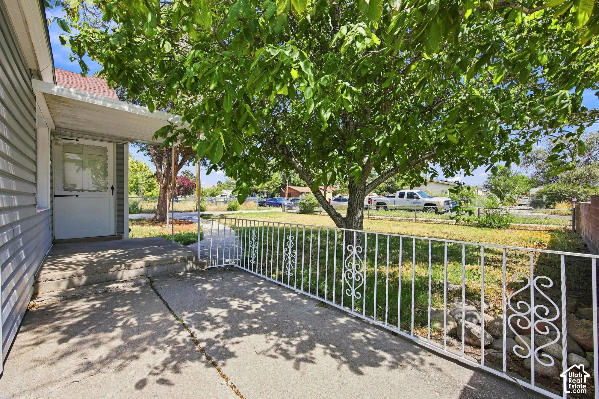 Covered porch entry featuring a storm door, concrete steps, and a decorative white metal railing
