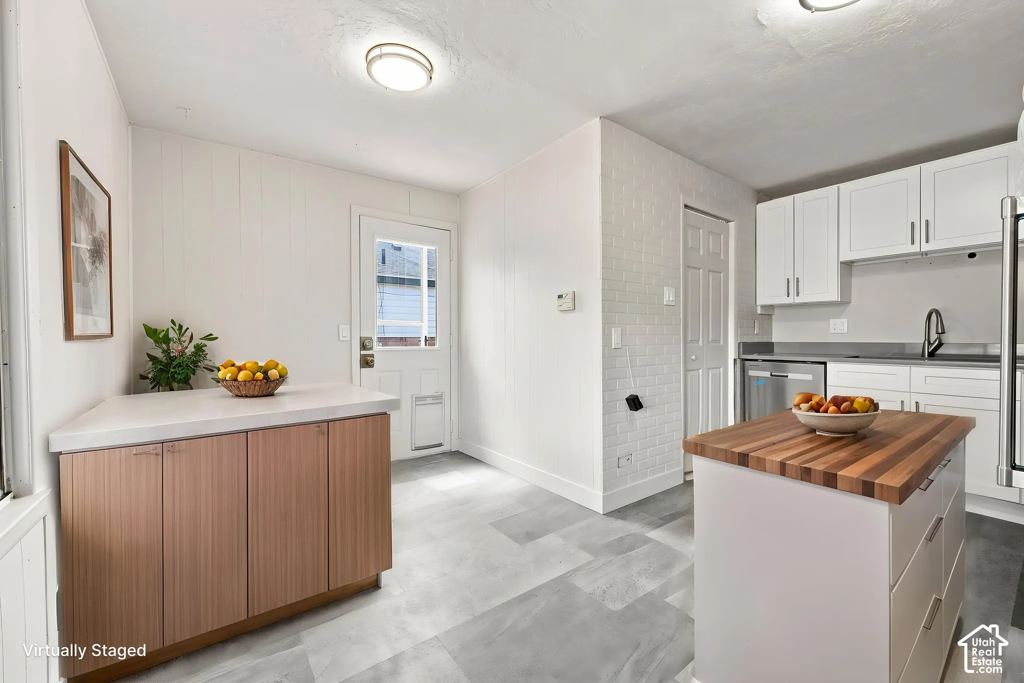Kitchen featuring white shaker-style cabinetry, wood-finish lower cabinetry, stone-style countertop, a mobile center island with a wood-block surface, and patterned tile flooring