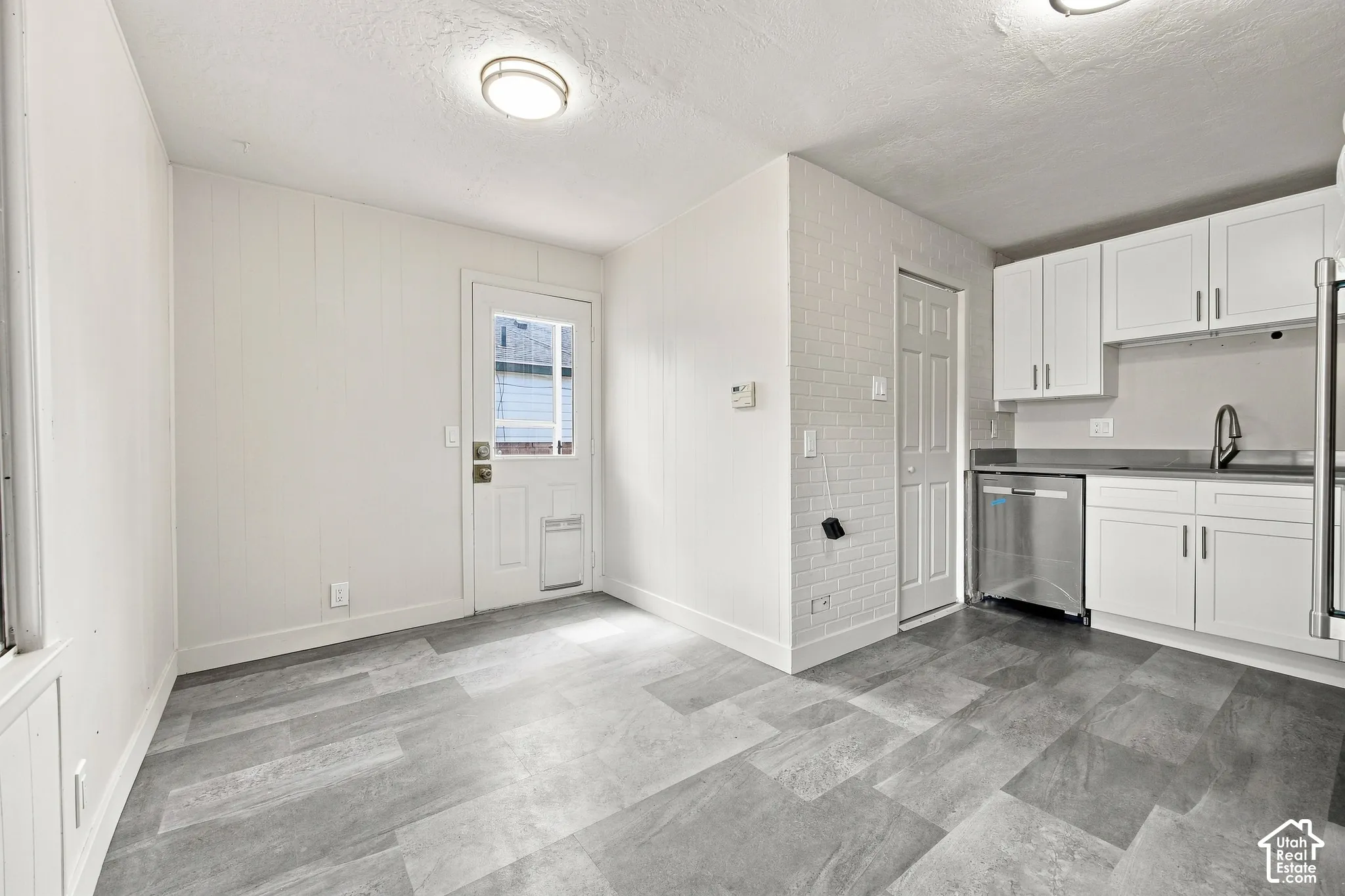 Updated kitchen featuring white shaker cabinets, stainless steel appliances, and a durable gray countertop