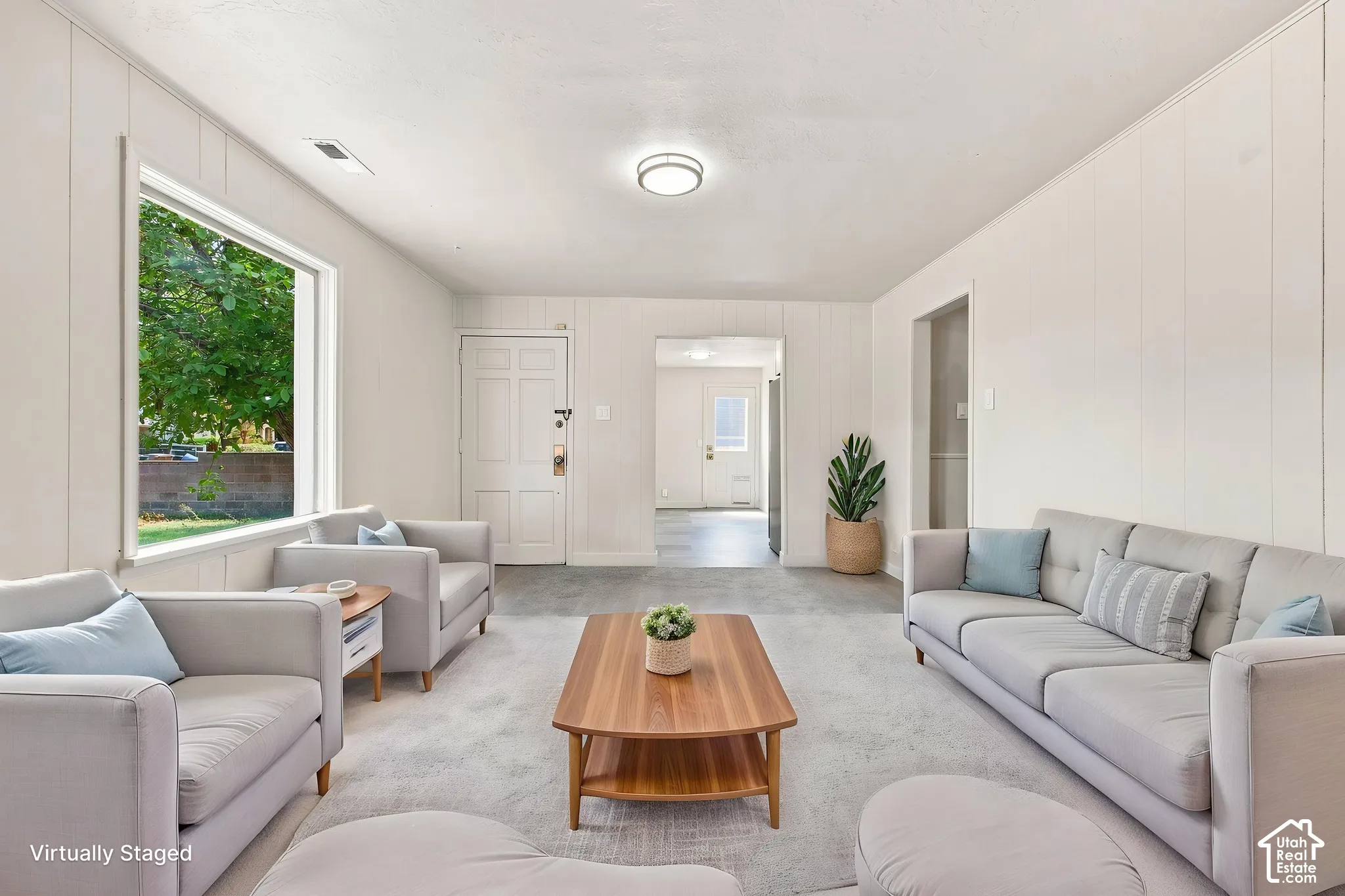 Neutral interior featuring panel walls, neutral carpeting, a large picture window, and a flush-mount ceiling light fixture