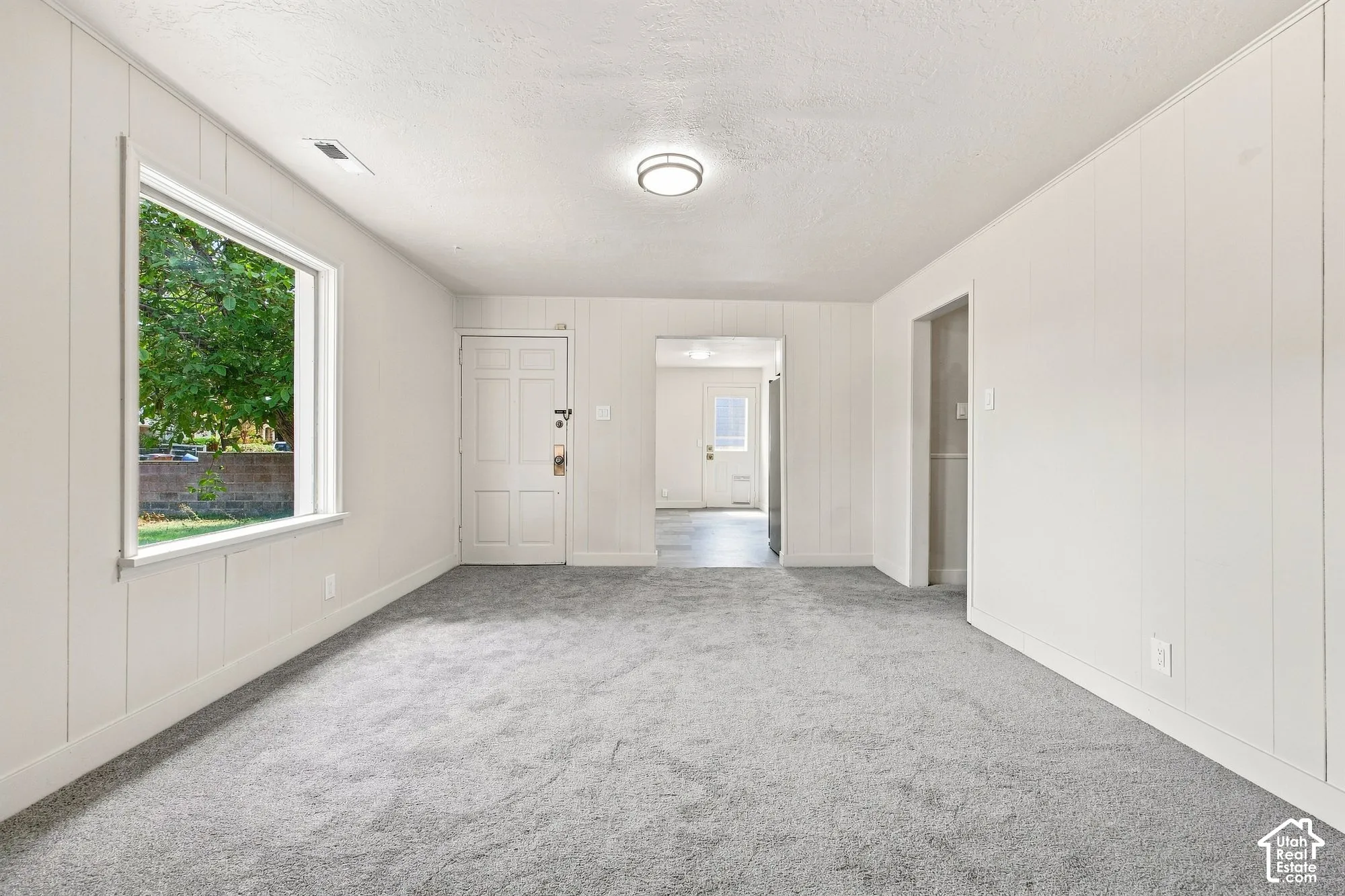 Gray carpet flooring, white paneled walls, white trim, recessed lighting, and a white interior door