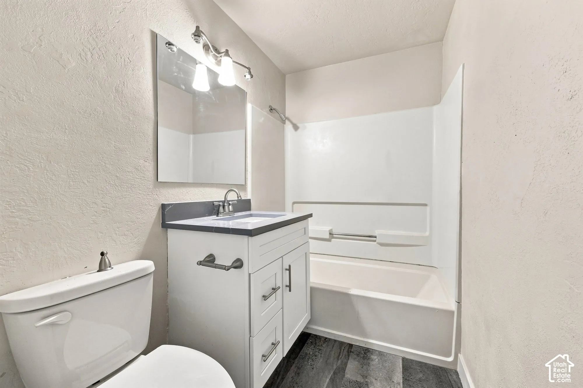 White vanity with brushed nickel hardware, integrated sink, and dark countertop