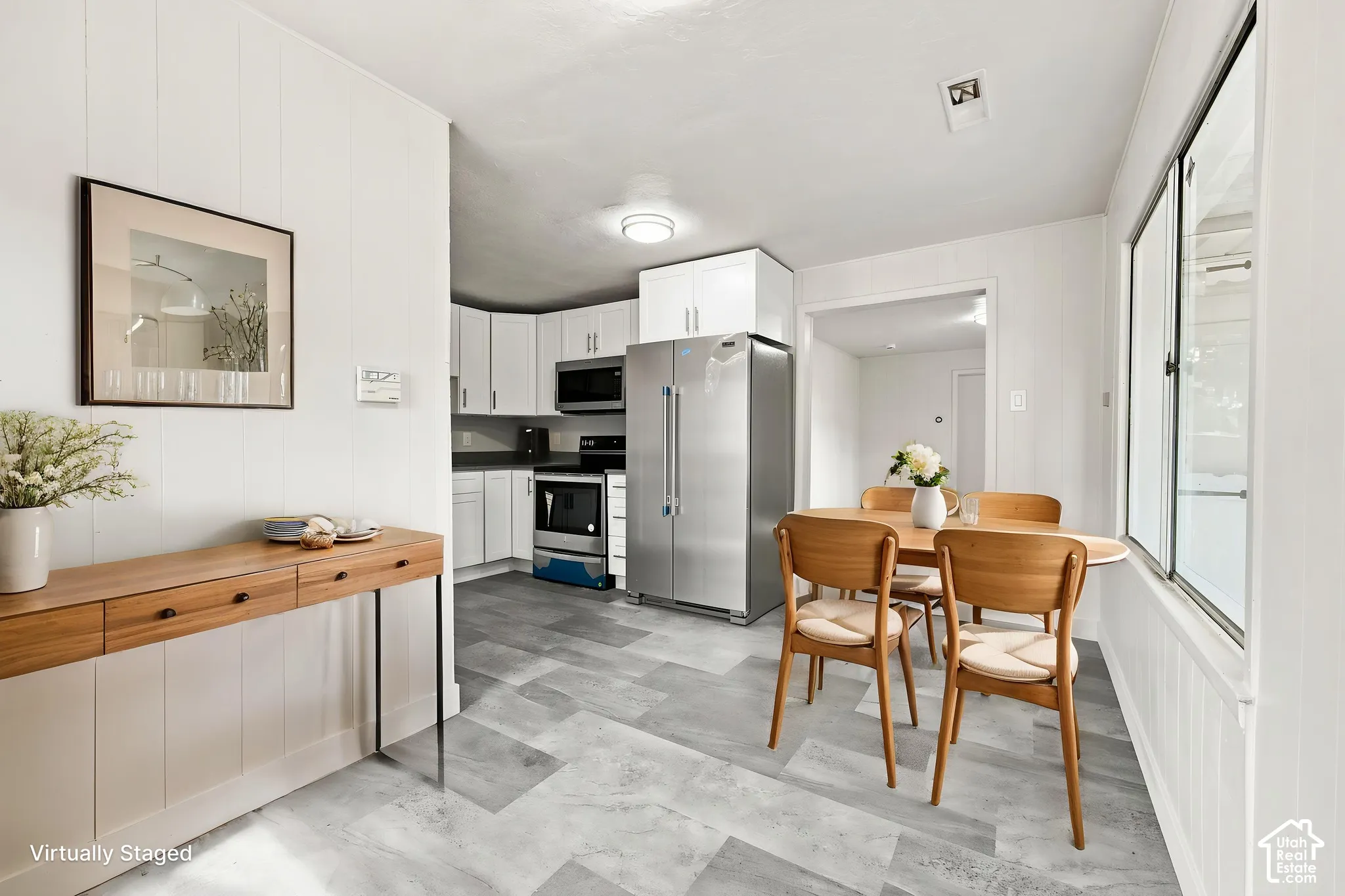 Kitchen featuring white cabinetry, stainless steel appliances, and multi-tonal gray tile flooring