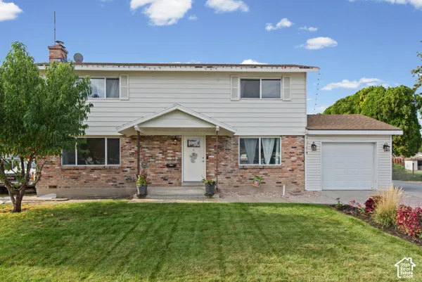Two-story property featuring brick and siding exterior, an attached garage, covered entryway, and a front lawn