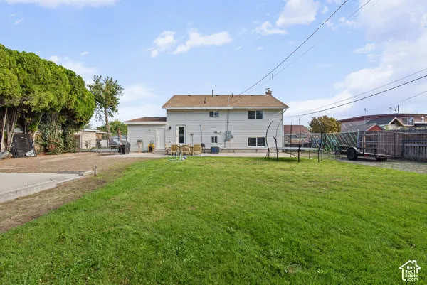 Expansive grassy lawn with a concrete patio, wood fencing, and mature perimeter trees