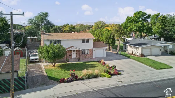 Two-story residence with a brick and siding exterior, front lawn, mature landscaping, and an attached two-car garage