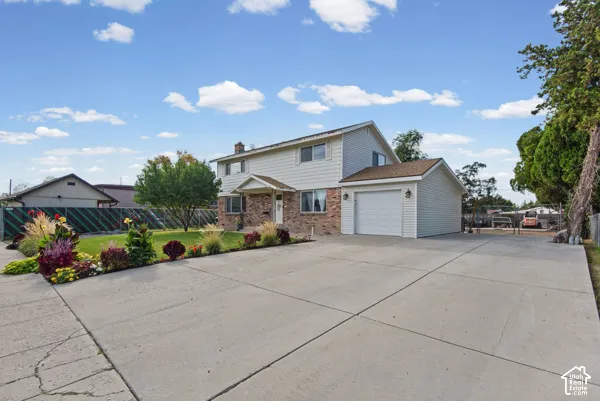 Two-story residence featuring brick and siding exterior, an attached garage, and a wide concrete driveway