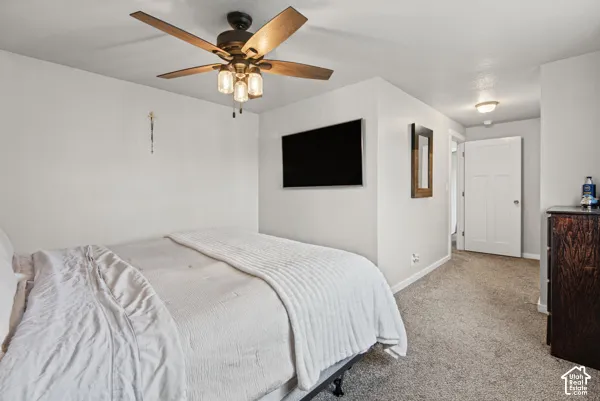 Ceiling fan with integrated lighting, wall-mounted television, and neutral-toned carpeting