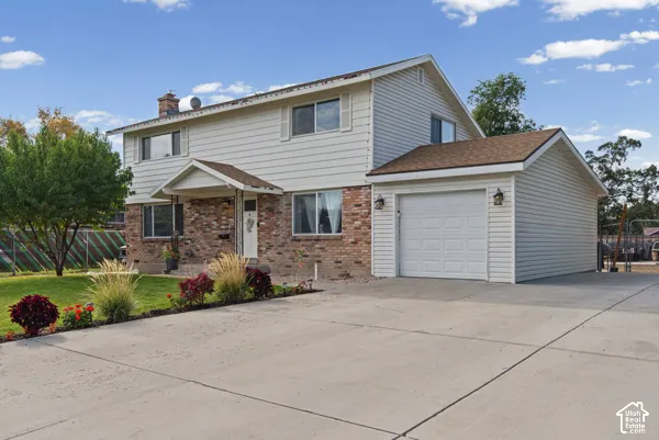 Two-story residence featuring a brick and siding exterior, an attached garage, a peaked portico entrance, and a concrete driveway