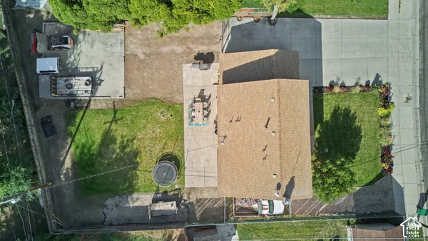 Paved driveway, expansive concrete patio, mature landscaping, and a well-maintained roof