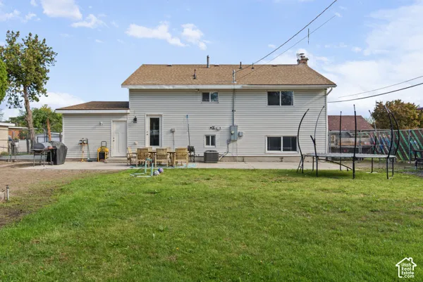 Spacious backyard featuring a large green lawn, concrete patio, and light-colored siding