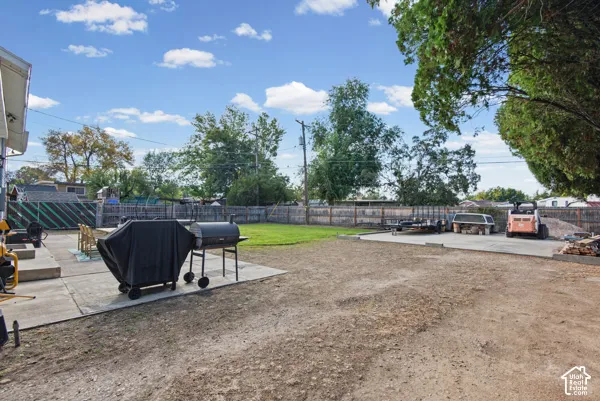 Expansive outdoor space featuring a concrete patio, a gravel area, a grass lawn, and mature trees