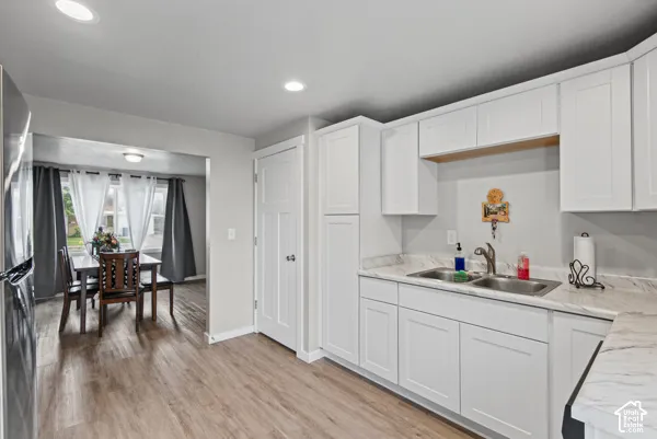 Kitchen featuring white shaker-style cabinetry, wood-finish flooring, recessed lighting, and a double-basin stainless steel sink