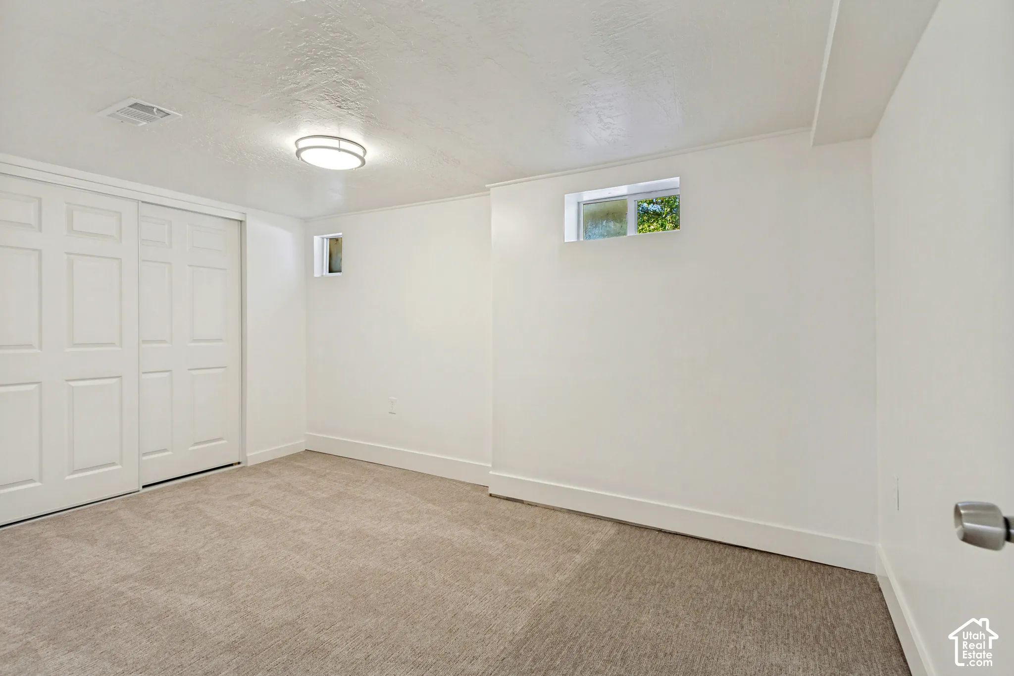 Neutral carpet flooring, white walls, built-in sliding closet doors, and recessed windows