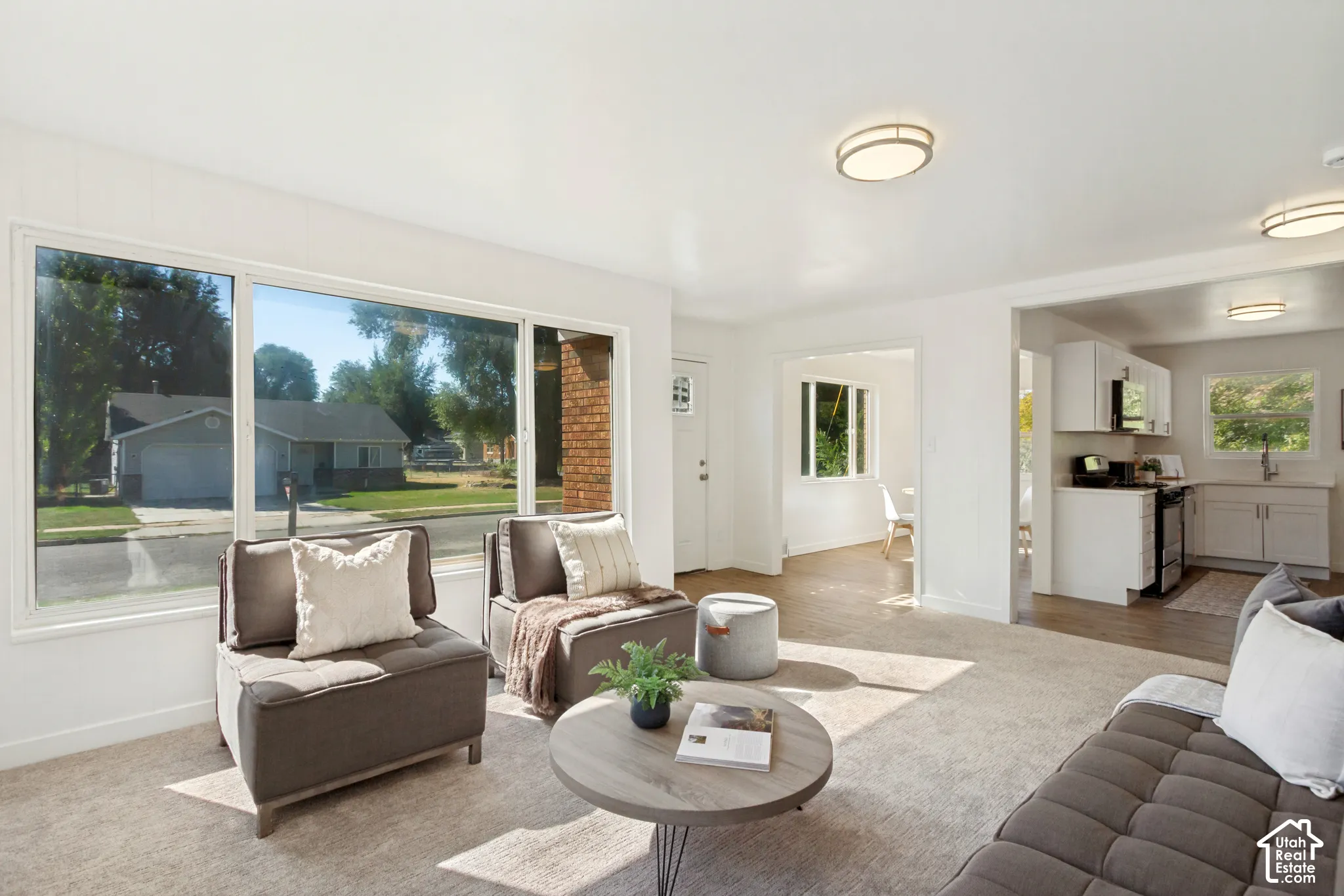 Bright living space featuring large windows, light-toned carpeting, and recessed lighting