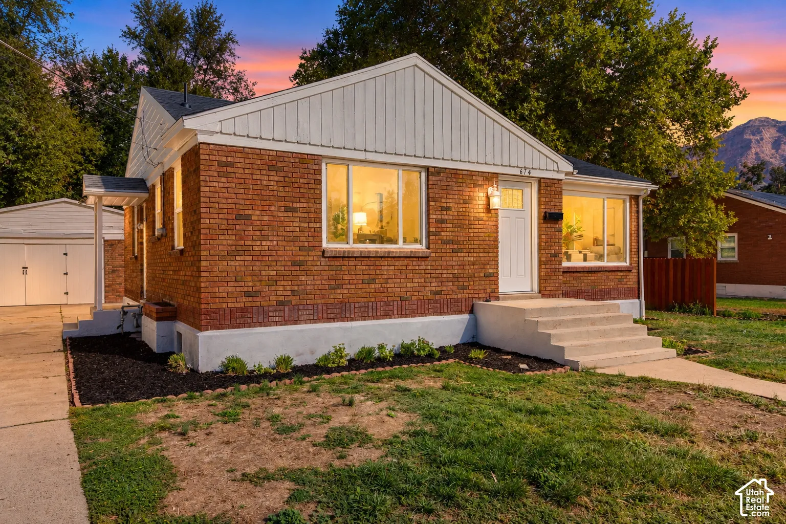 Brick exterior, white siding accents, concrete steps, attached two-car garage, and a manicured front lawn