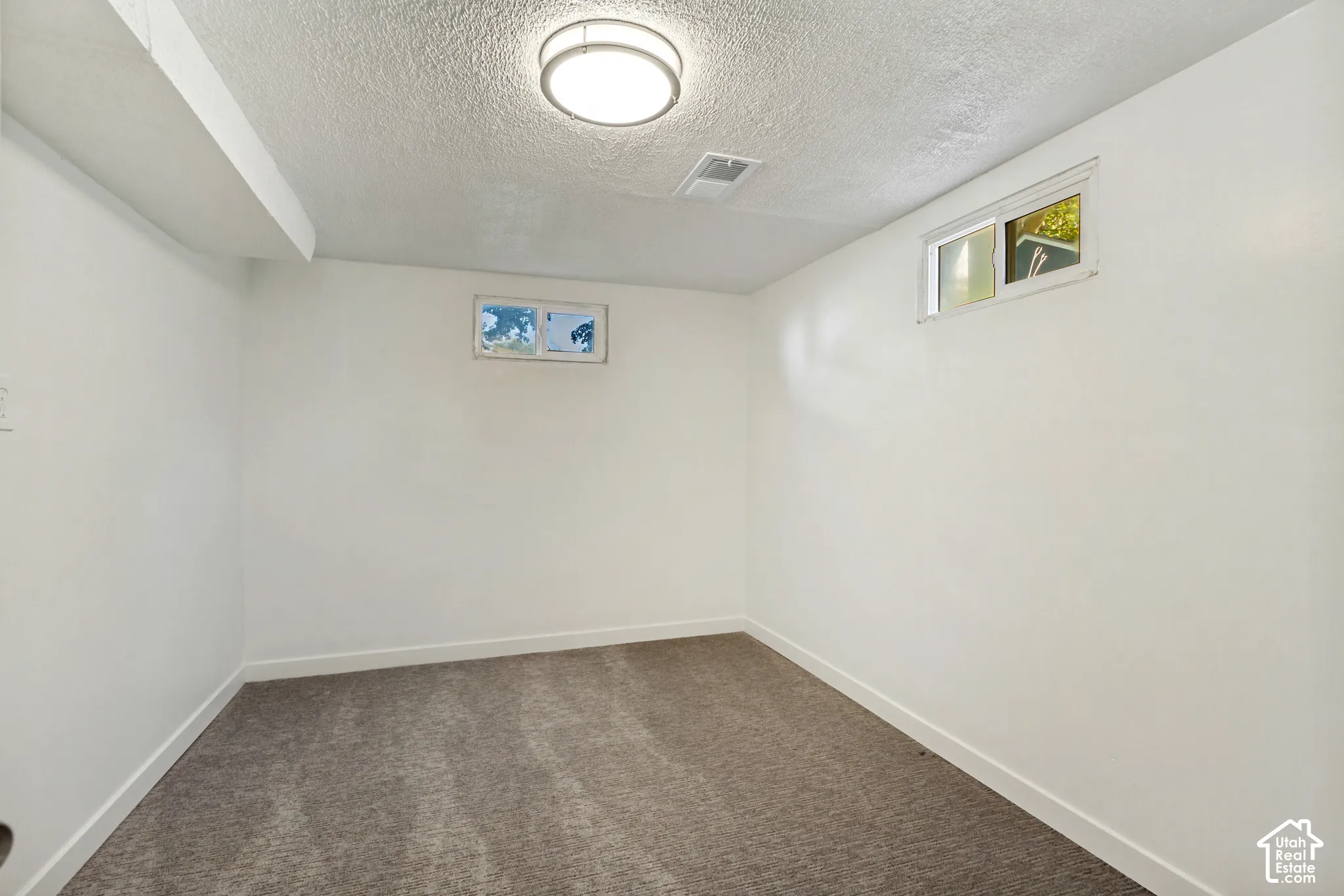 Recessed lighting fixture, two transom windows, and neutral carpeting