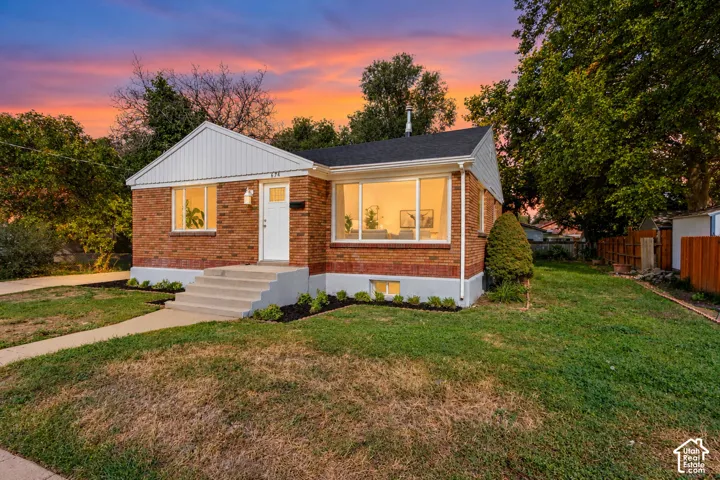 Brick exterior with white siding accents, concrete walkway, and established landscaping
