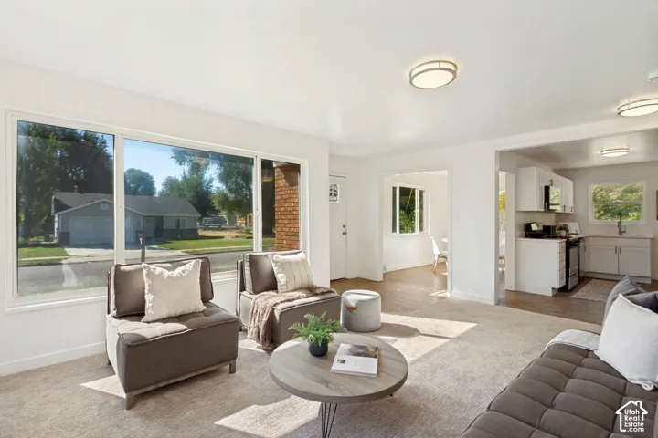 Bright living space featuring large windows, light-toned carpeting, and recessed lighting