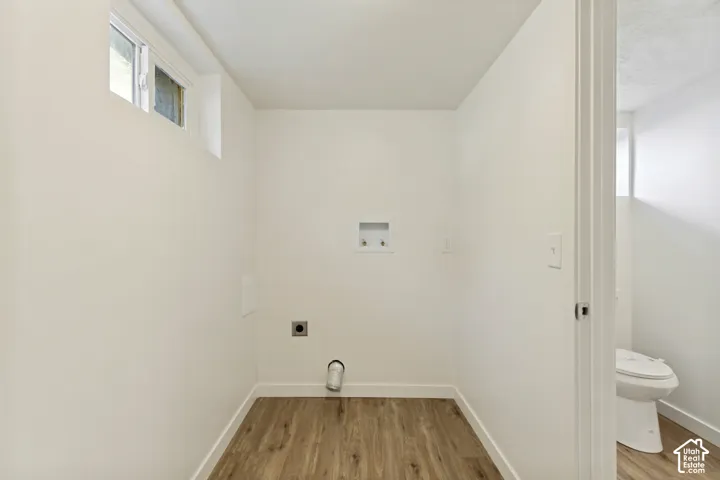Dedicated laundry area with wood-finish flooring, a high-set window, and connections for appliances