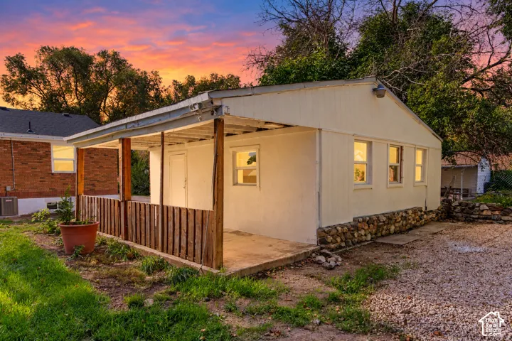 Building with a covered porch, stone foundation, and multiple windows