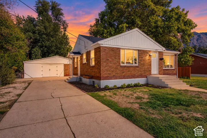 Brick exterior with white trim, concrete driveway, and detached garage