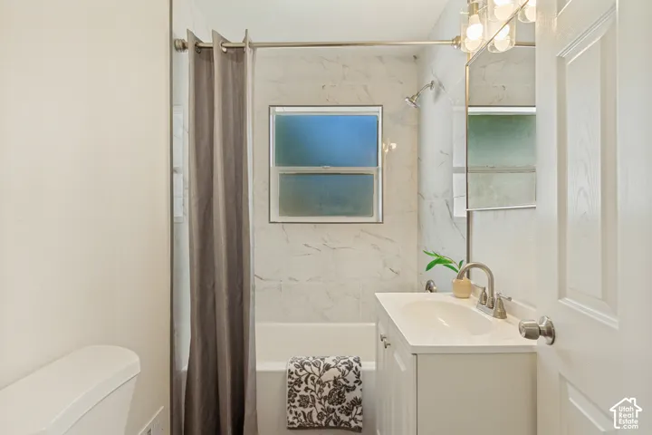 White vanity with a rectangular basin sink, chrome faucet, and mirrored medicine cabinet