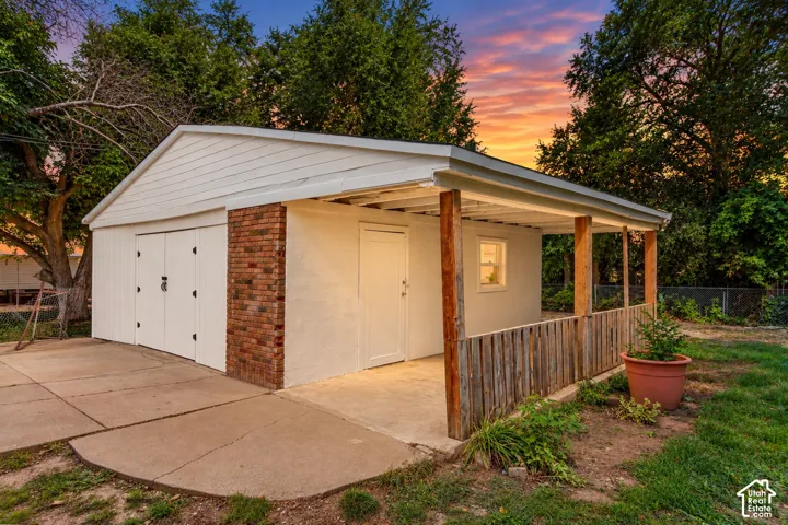 Detached garage structure featuring white siding, brick accents, and two garage doors