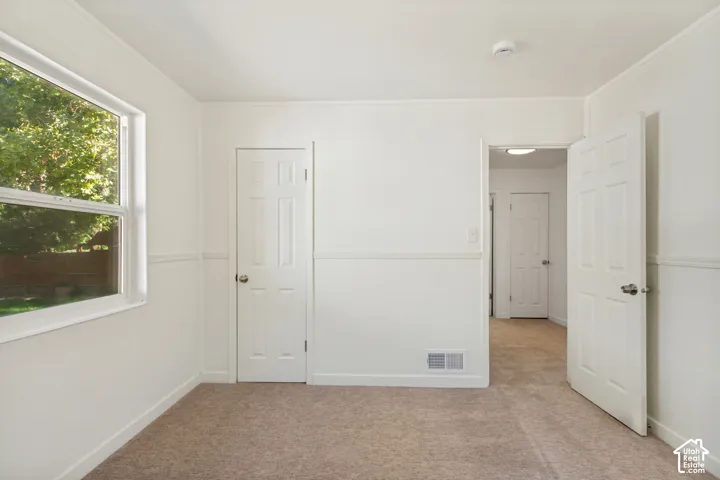 Neutral wall color, wall paneling, light-colored carpet, white trim, and a window with exterior views