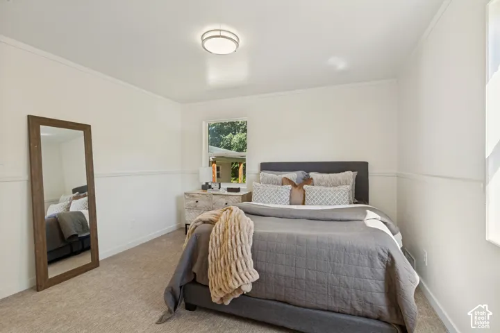 Carpeted flooring, white walls with chair rail molding, ceiling-mounted light fixture, and a window providing natural light