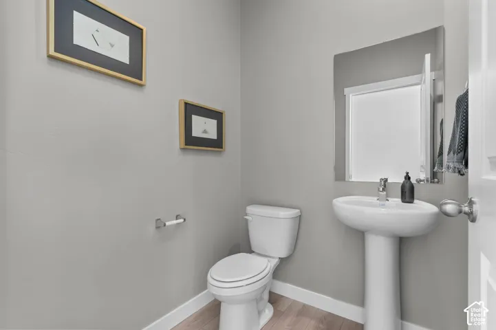 Pedestal sink with chrome faucet, framed mirror, and wood-finish flooring