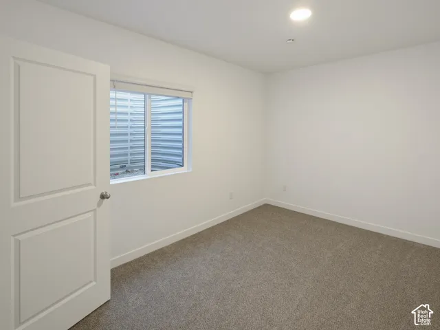 Recessed lighting, neutral-toned carpeting, white walls, white window trim, and a white interior door with paneling