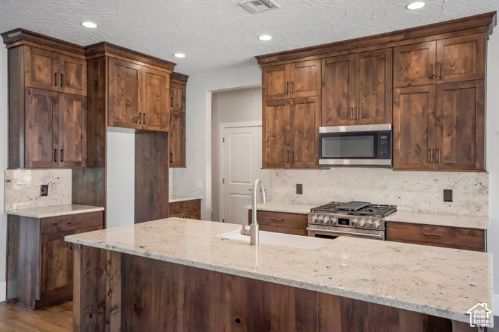 Kitchen featuring a center island, stainless steel appliances, wood cabinetry, and light-toned countertops