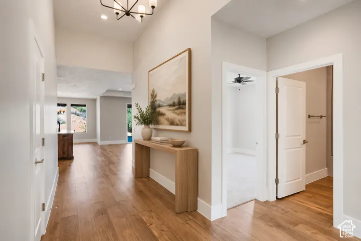 Vaulted ceiling entry with wood-finish flooring, recessed lighting, and a contemporary chandelier