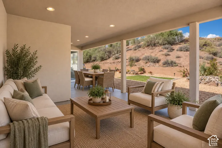 Covered outdoor patio with recessed lighting, concrete flooring, and an expansive sloped natural landscape