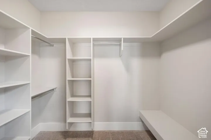 Built-in white shelving, multiple hanging rods, corner shelving unit, built-in bench, and carpeted flooring