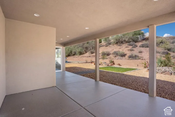 Expansive covered patio with recessed lighting, concrete flooring, and surrounding rock landscaping