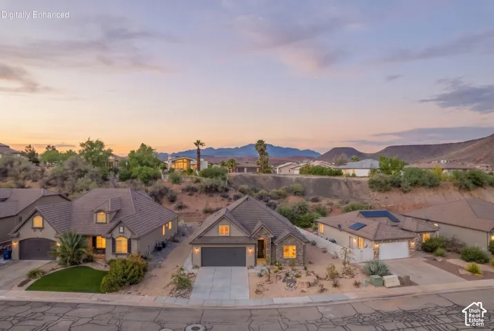 Southwestern-style residence featuring a tile roof, an attached two-car garage, and a landscaped front yard with desert-adapted plants