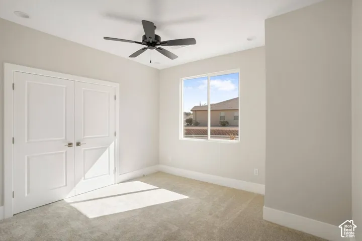 Carpeted room featuring a ceiling fan, recessed lighting, double panel doors, and a large window