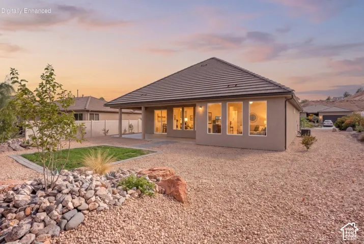 Stucco exterior with a tiled roof, multiple large windows, and a covered patio