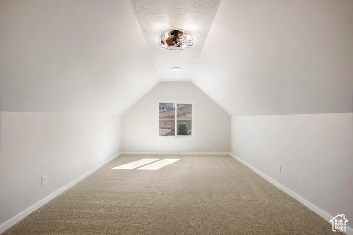 Carpeted room with a vaulted ceiling and a centered window