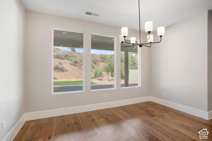 Recessed lighting, wood-finish flooring, contemporary chandelier, multiple windows, and a neutral color palette