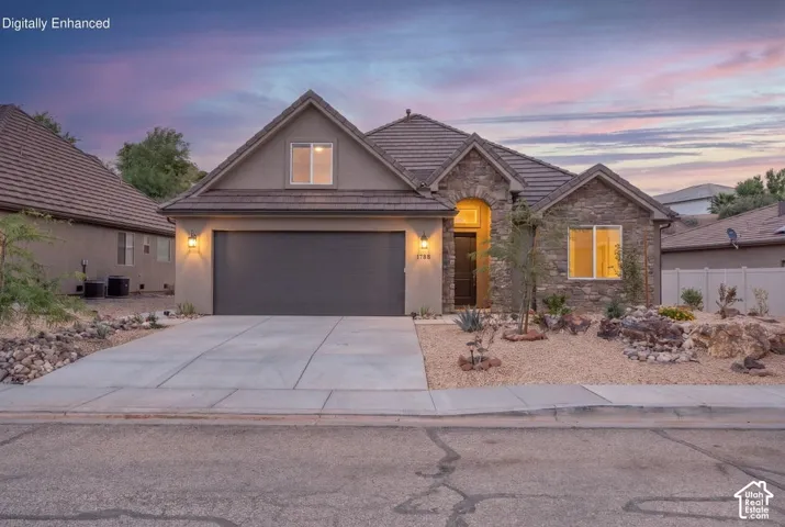 Exterior featuring stone and stucco finishes, a paved driveway, and an attached garage