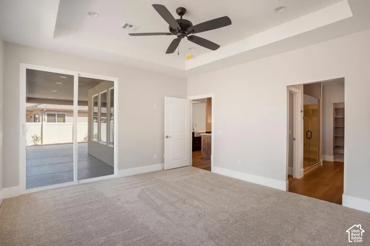 Recessed ceiling with a matte black ceiling fan, light gray wall paint, light gray carpeting, and sliding glass door