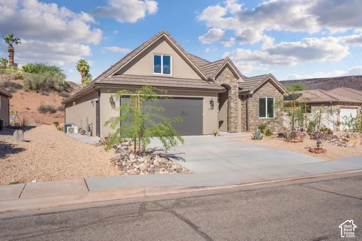 Stucco exterior with stone accents, a multi-gabled roof, and an attached garage