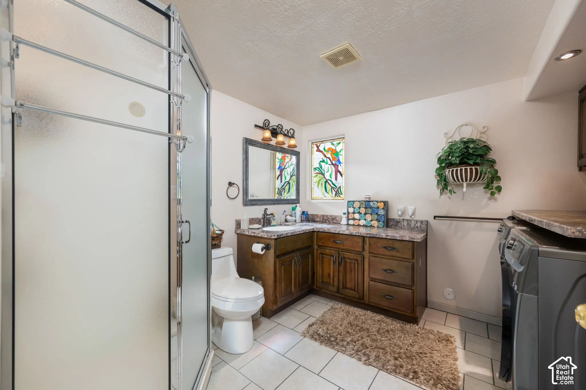 Frosted glass shower enclosure, wood-finish vanity with countertop, built-in cabinetry, and tile flooring