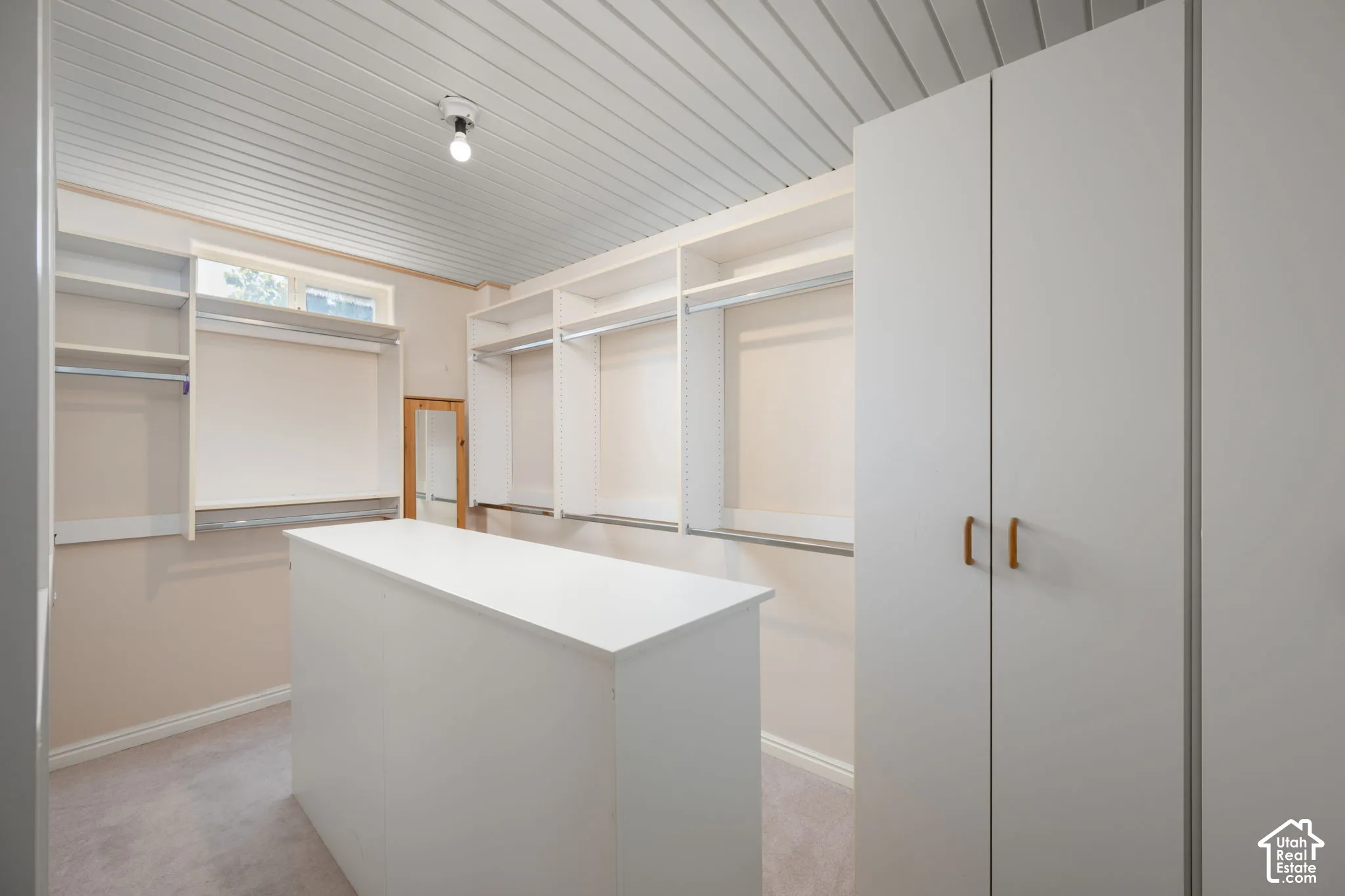 Built-in cabinetry with multiple hanging rods, shelving, and a central storage island