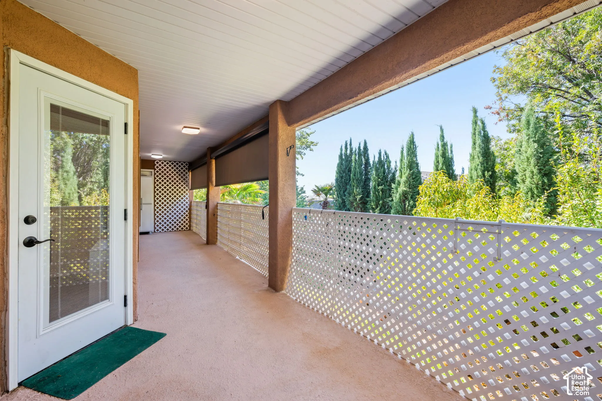 Covered outdoor space featuring a white lattice railing and a glass-paneled door